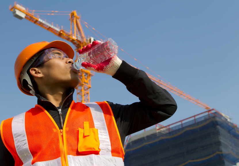 worker man as he drinks from a plastic water bottle